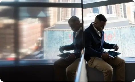 A man using a tablet while sitting next to a window
